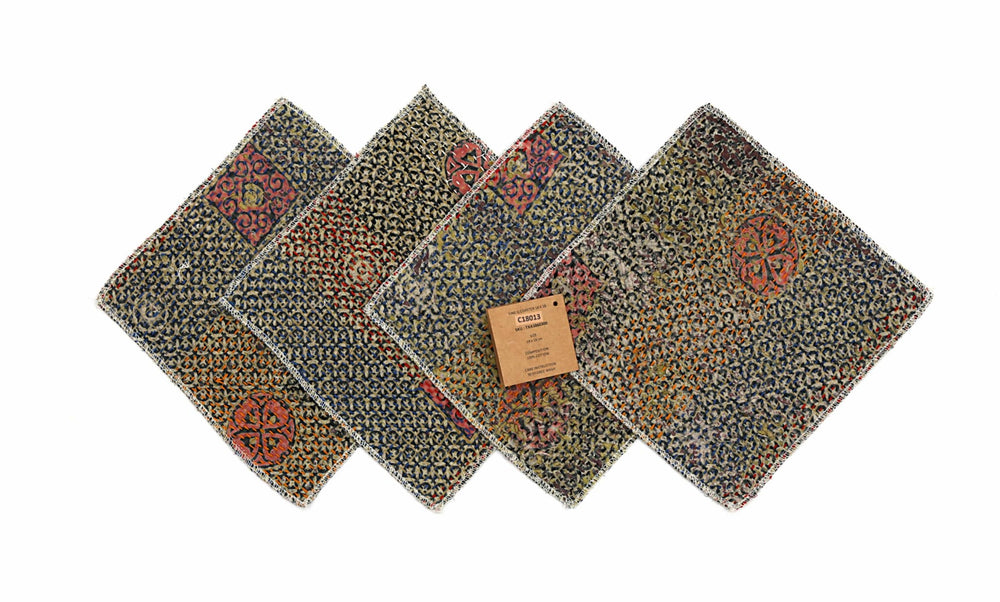 Set mit 4 Untersetzern (18 x 18 cm) mit blauem Webmuster und farbenfrohen orange/roten abstrakten Ornamenten, eingefasst mit weißen Fransen.